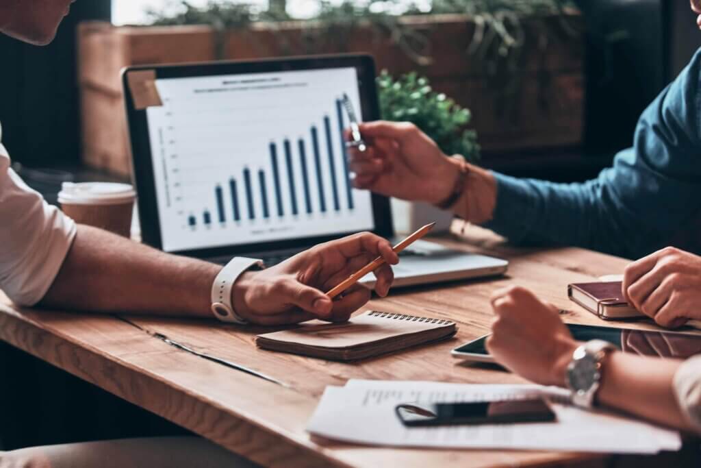 Hands pointing at tablet showing bar chart while reviewing lease documents and paperwork on desk.