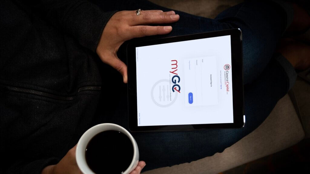 Hands holding tablet showing customer portal login page with coffee cup nearby.