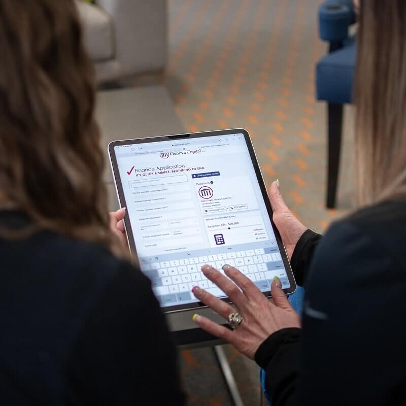 Hands typing on tablet displaying online application form with virtual keyboard visible.