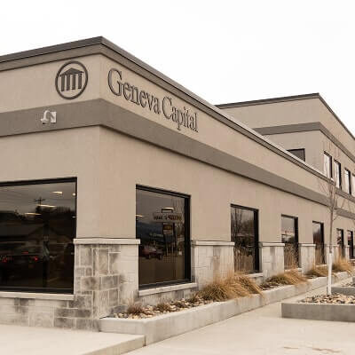 Tan and stone corporate building with "Geneva Capital" signage and classical columns logo on exterior facade.