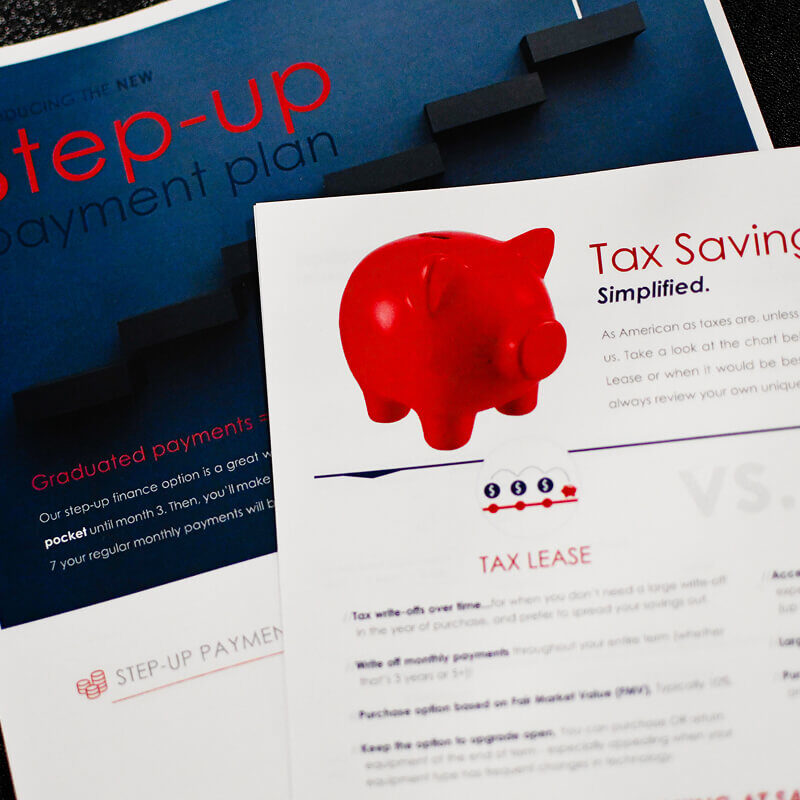 Small red piggy bank sitting on top of financial planning brochures about step-up payment plans and tax savings programs.