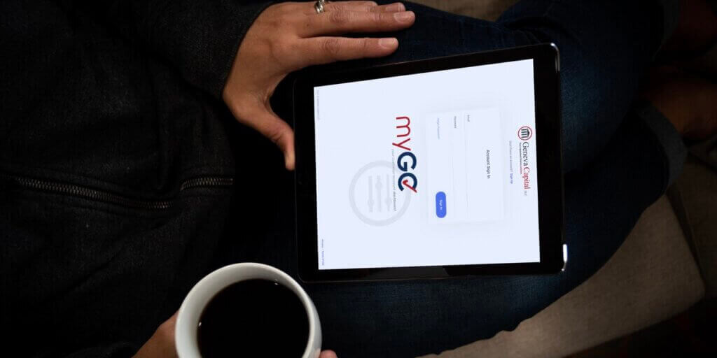 Hands holding tablet showing customer portal login page with coffee cup nearby.