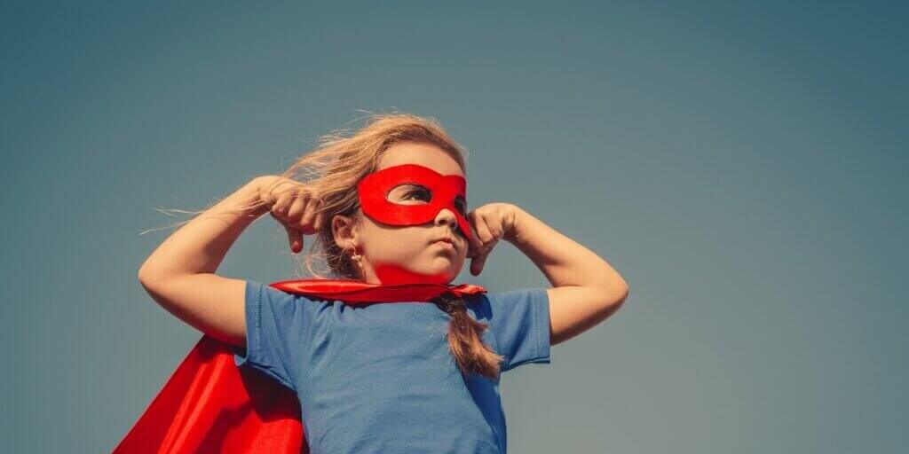 Child in red superhero mask and cape with hands on hips in confident pose representing professional tradeshow expertise.